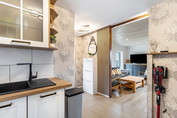 A modern kitchen with a black sink, white cabinets, and a wooden countertop.