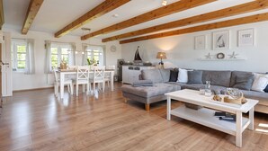 A spacious living area with a dining table, sofa, and a white coffee table. - Holiday Home 'Ferienhaus Pellworm Findling' with Terrace,  Garden and Wi-Fi (Pellworm)