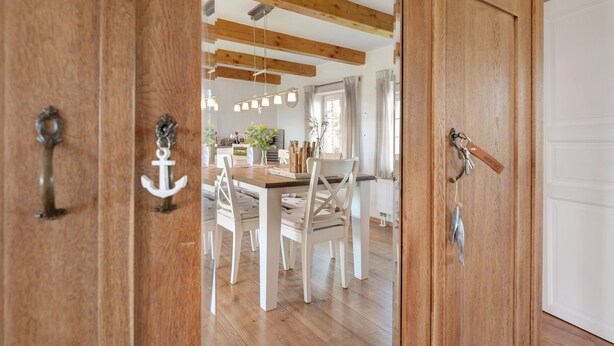 A wooden door with an anchor handle, leading to a dining area with a wooden table and white chairs. - Holiday Home 'Ferienhaus Pellworm Findling' with Terrace,  Garden and Wi-Fi (Pellworm)