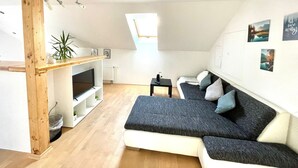 Ein Loft-Wohnraum mit integriertem Fernseher, einer Couch, einem kleinen Tisch und einer Pflanze.