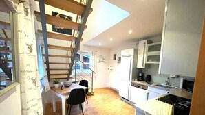 Eine moderne Küche mit weißen Schränken, einer Holztreppe und einem Essbereich mit Tisch und Stühlen.