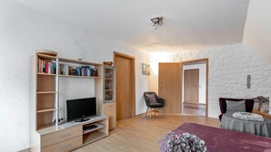 Une chambre à coucher moderne, équipée d’une télévision, d’une bibliothèque et d’un grand lit.
