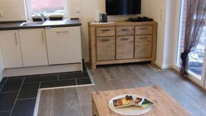 Cocina compacta con pileta, alacenas y un televisor sobre la encimera.