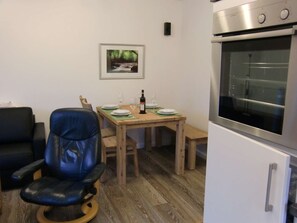 A dining area with a wooden table, chairs, a framed picture on the wall, and a modern oven.