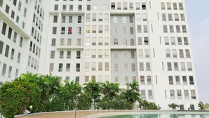A modern building with a pool area, featuring a curved pool and a staircase leading to a terrace. - Amerta Room Patraland Urbano (Bekasi)