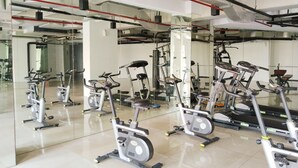 A gym with multiple exercise bikes and mirrors on the walls. - Amerta Room Patraland Urbano (Bekasi)