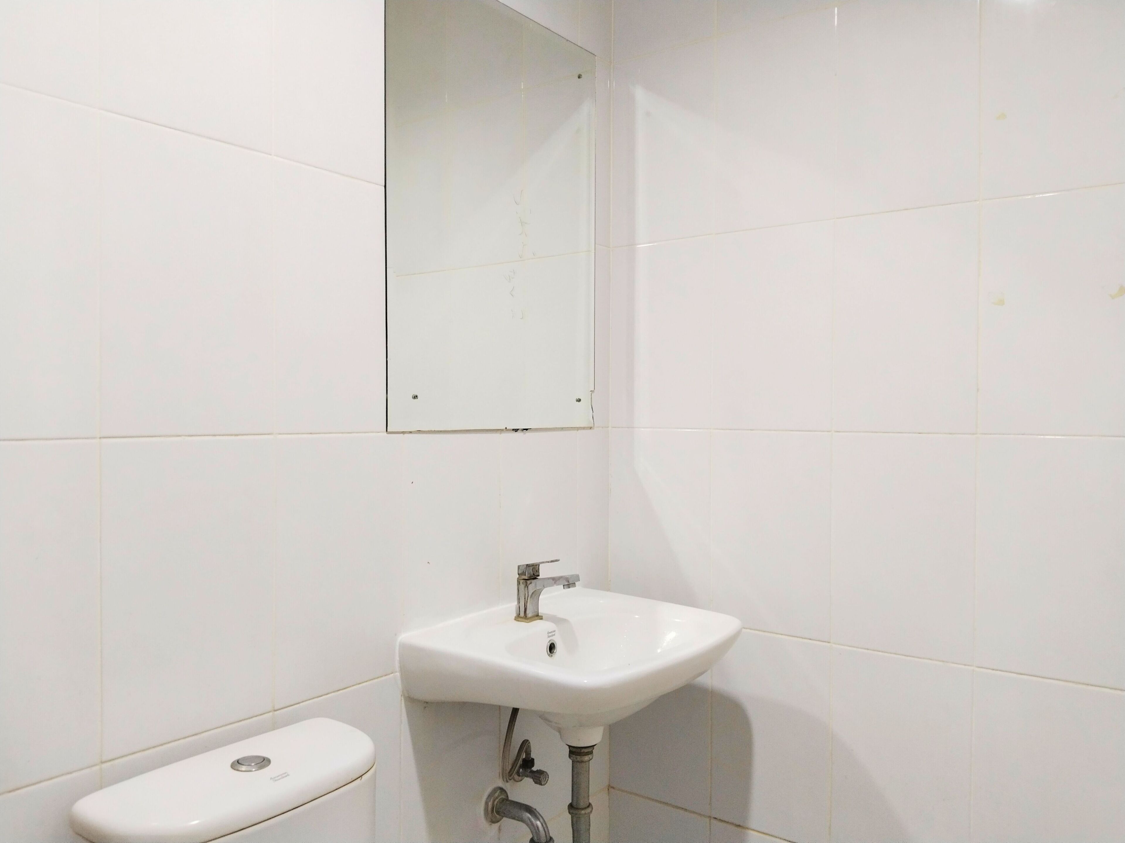 A bathroom with a white sink, a toilet, and a mirror on the wall.