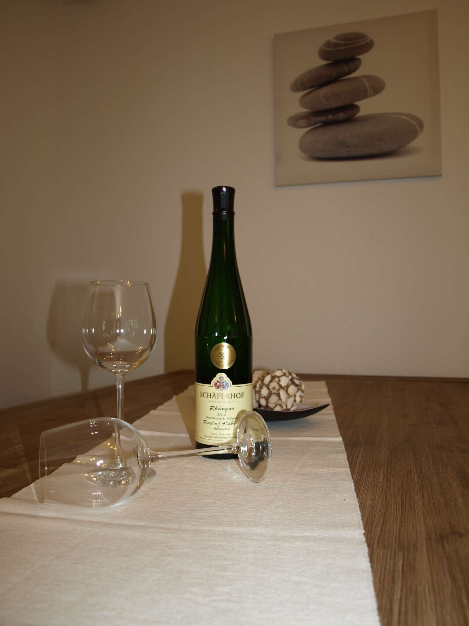 En vinflaske, to vinglas og en dekorativ sten kugle på et bord.