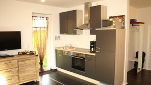 Una cocina moderna con armarios oscuros, un microondas y una cafetera.