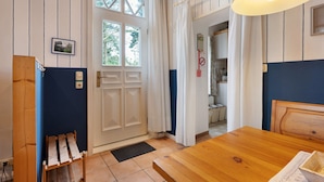 A room with a wooden table, a door with a window, a blue wall, and a wooden headboard. - Apartment 'Große Ferienwohnung' with Shared Terrace, Shared Garden and Wi-Fi (Leck)