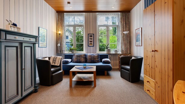 A cozy room with a sofa, two armchairs, a wooden cabinet, and a large window with curtains. - Apartment 'Große Ferienwohnung' with Shared Terrace, Shared Garden and Wi-Fi (Leck)