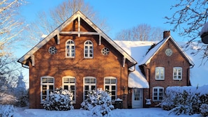 A large brick house with a snow-covered driveway and surrounding trees. - Apartment 'Große Ferienwohnung' with Shared Terrace, Shared Garden and Wi-Fi (Leck)