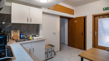 Eine moderne Küche mit weißen Schränken, einem eingebauten Herd und einem Essbereich mit Holztisch und Stühlen.