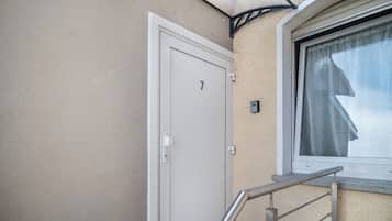 A door with the number 7, a window with a curtain, and a metal handrail.