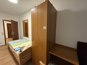 A bedroom with a bed, a wooden wardrobe, a mirror, and a desk. - Room 'Zimmer 8' with Wi-Fi (Berg-Weiler)