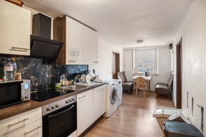 A compact kitchen with a microwave, stove, oven, and washing machine.