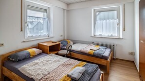 A dormitory room with two wooden beds, a small desk, and a radiator. - Room 'Zimmer 10' with Wi-Fi (Berg-Weiler)