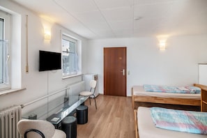 A room with a bed, a desk, a chair, a TV, and a door. - Room 'Zimmer 12' with Wi-Fi (Berg-Weiler)