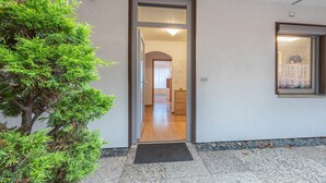 A doorway leading to a room with a wooden floor, a small rug at the entrance, and a window with a curtain. - Apartment 'Das Spatzennest' with Sauna, Mountain Views & Private Terrace (Bad Harzburg)
