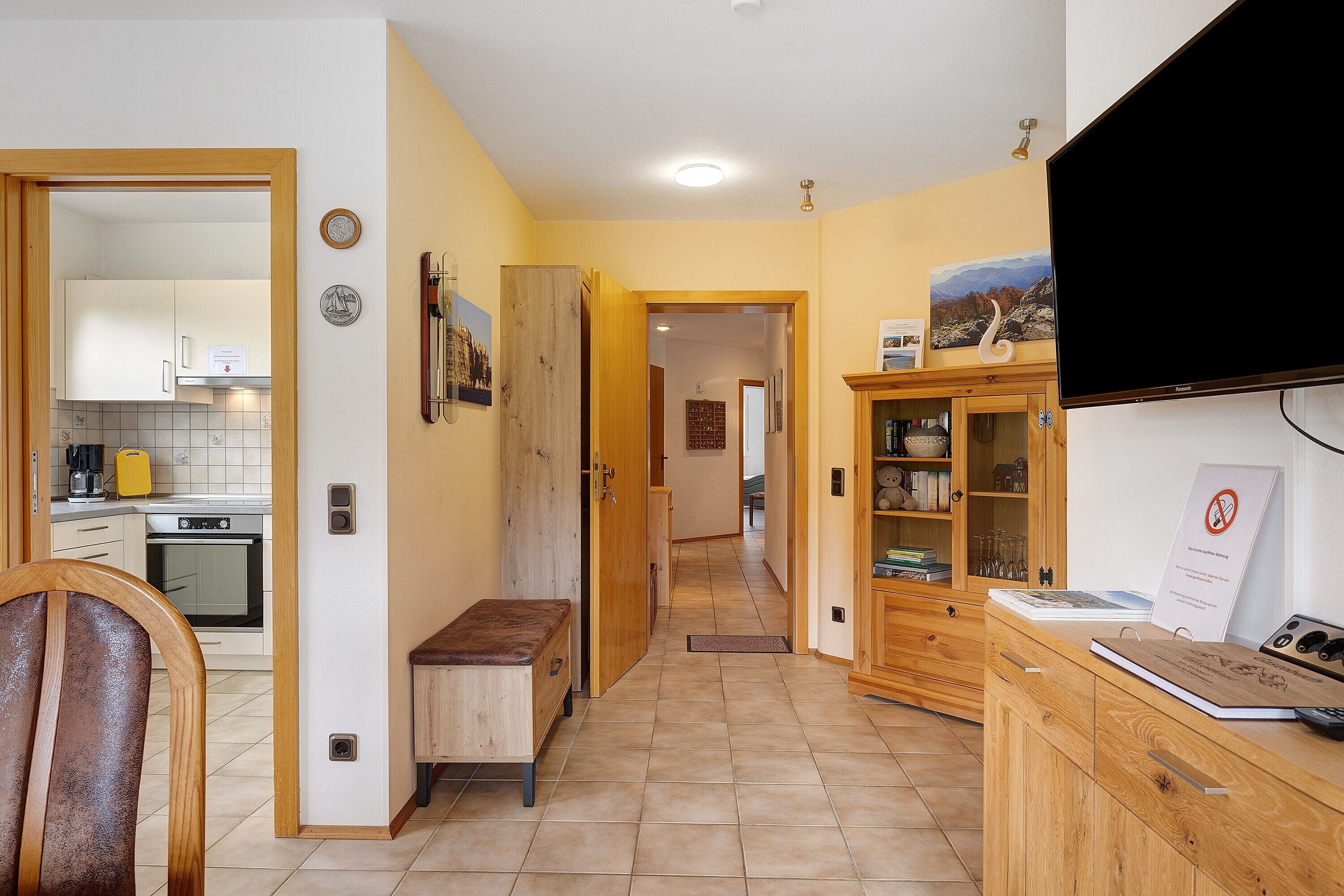 A kitchen with cabinets, a bench, and a dining area with a chair.