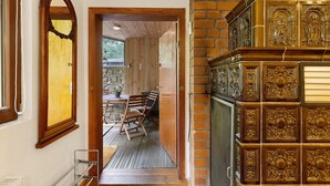 A wooden interior with a brick wall, a wooden door, and a dining area with chairs and a table. - Bungalow 'Urlaubsoase Am Bruchsee' with Lake View, Private Terrace and Private Garden (Templin)