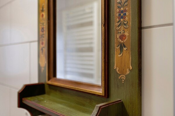 A mirror with ornate wooden frame and decorative elements.