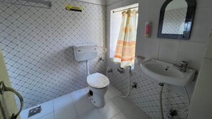 A bathroom with a toilet, sink, and a shower area.