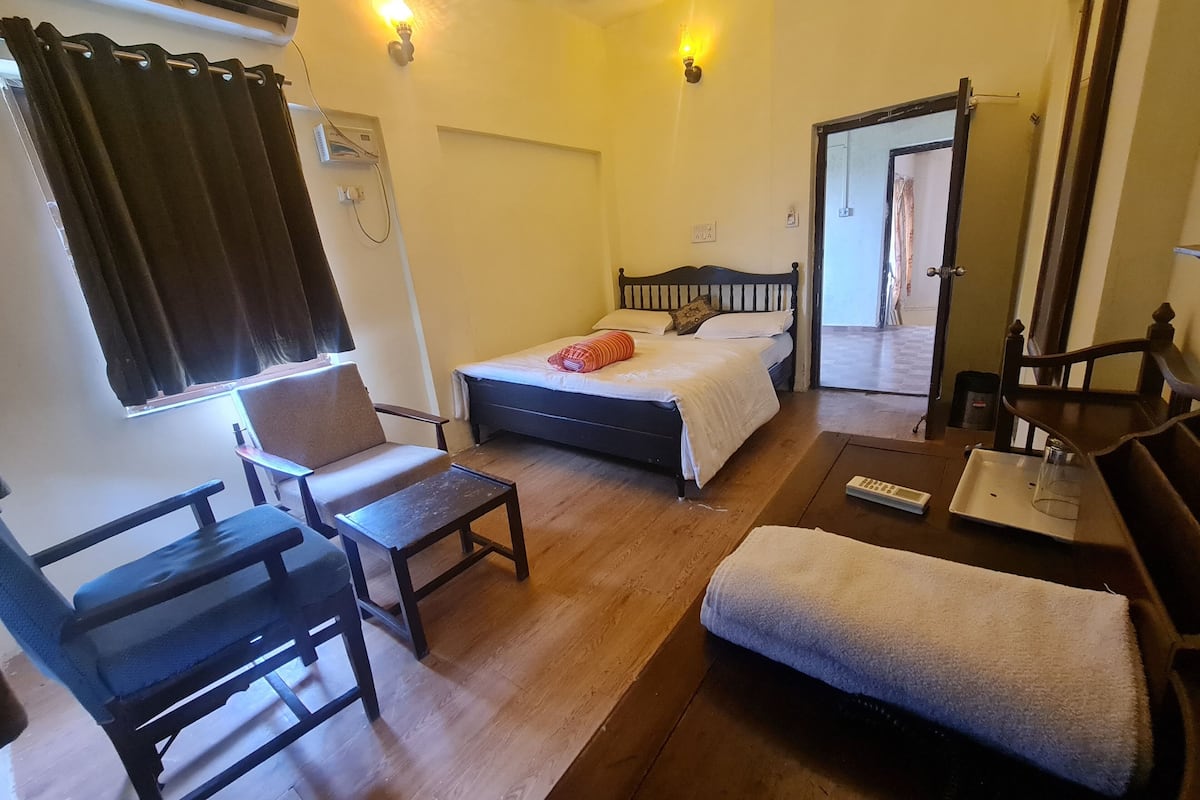 Una habitación de hotel con una cama, una silla, una mesita pequeña y suelo de madera.