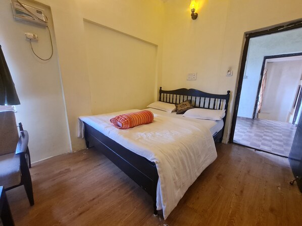 A bedroom with a bed, a chair, and a wall-mounted air conditioner.
