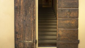 Une entrée d’immeuble avec une porte en bois et une lanterne fixée au mur.