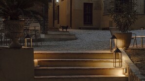 Une cour avec des marches en pierre menant à une porte, le tout entouré d’un bâtiment doté d’un balcon et d’une grande plante en pot.