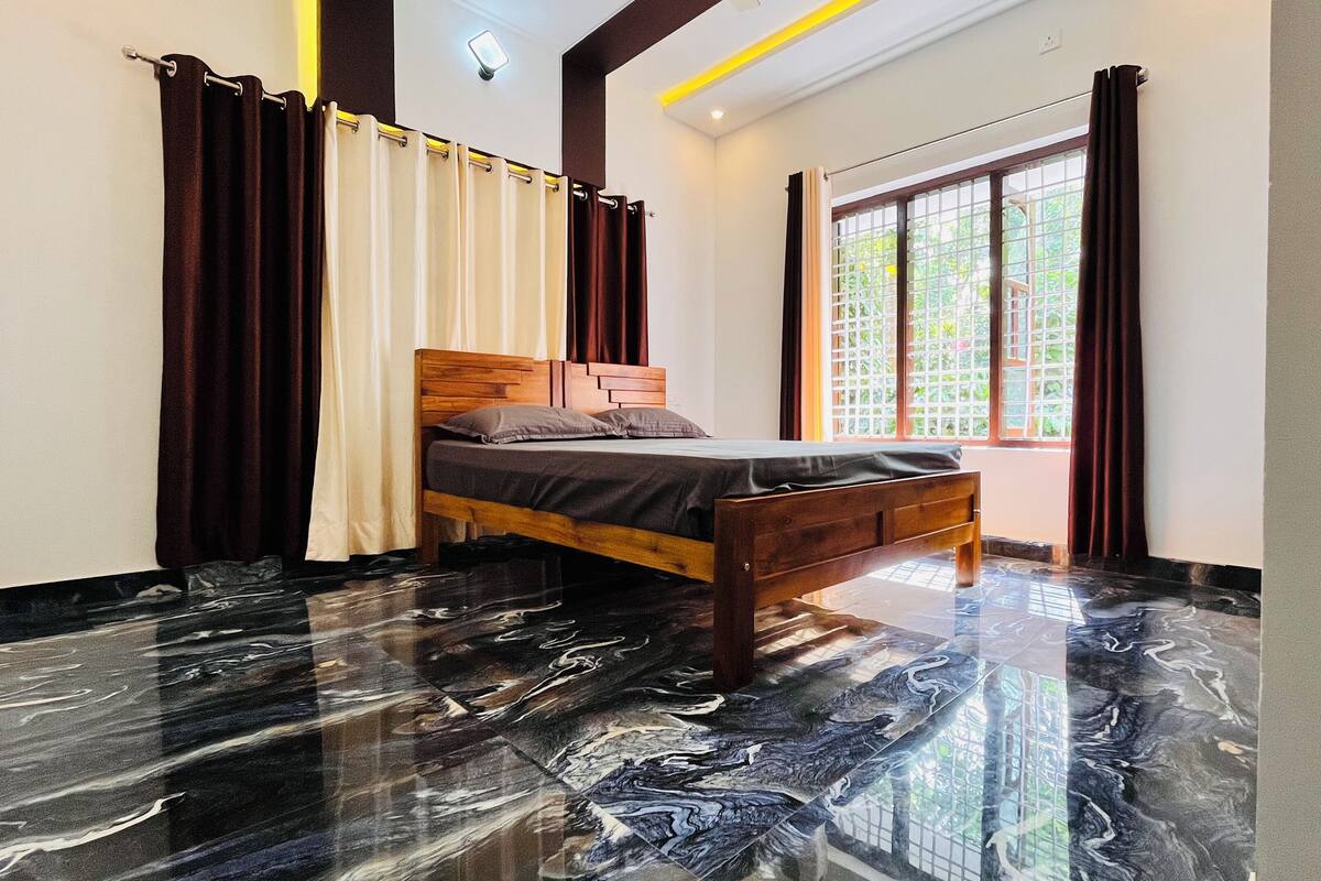 A bedroom with a wooden bed, a marble floor, and a window with curtains.