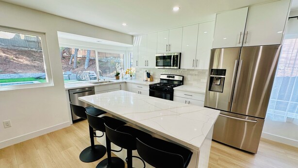 A modern kitchen with a large island, stainless steel appliances, and a view of the outdoors.