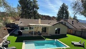 A modern house with a swimming pool, patio furniture, and a well-maintained lawn.