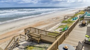 Eine Strandterrasse mit Sitzgelegenheiten im Freien und Blick aufs Meer.