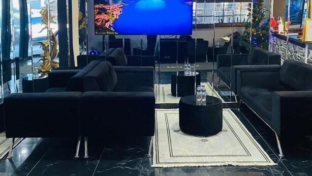 A modern lobby with a large flat-screen TV, black sofas, a coffee table, and a decorative Christmas tree. - Montenegro Suit Hotel (Eyup)