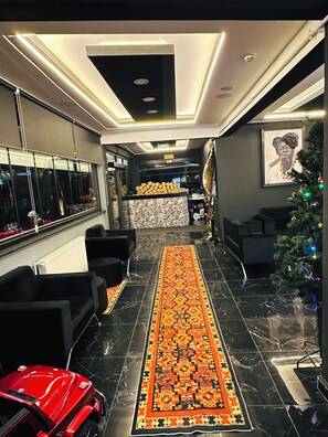 A hotel lobby with a black marble floor, a red sports car, a Christmas tree, and a patterned rug. - Montenegro Suit Hotel (Eyup)