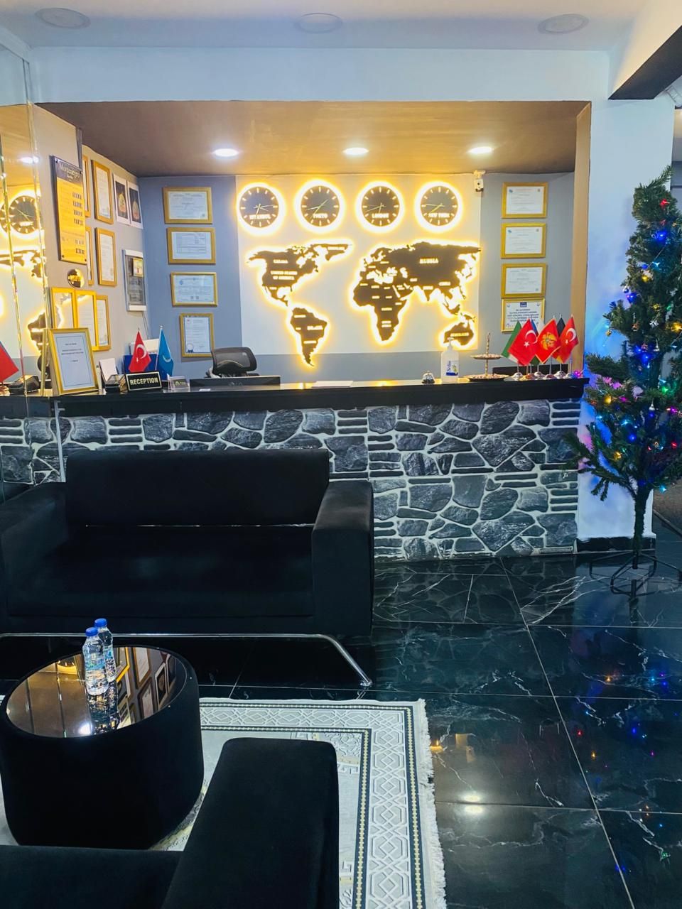 A reception area with a stone wall, a world map, framed certificates, and a Christmas tree.