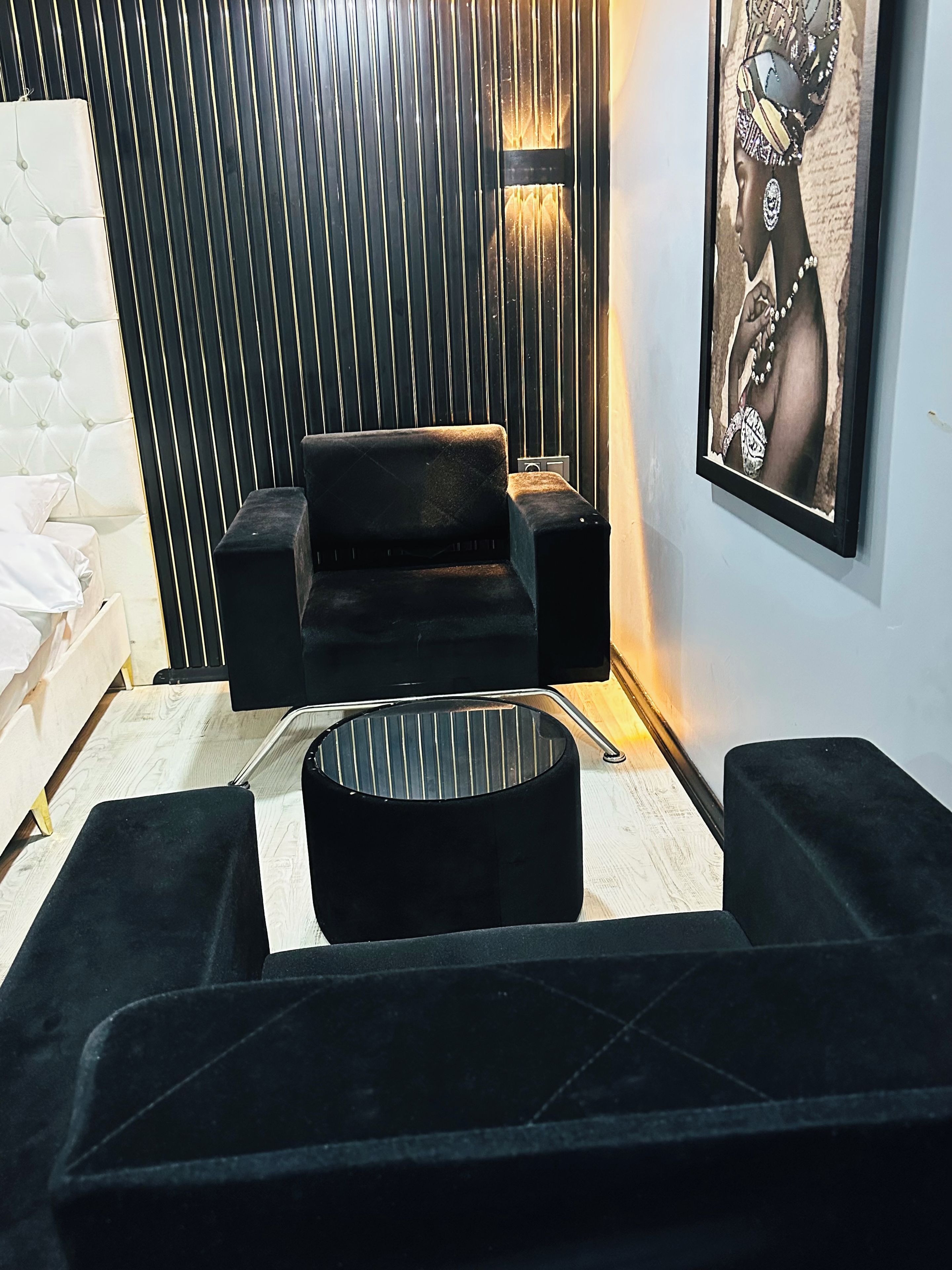 A modern living room with a black sofa, a round coffee table, and a wall-mounted speaker.