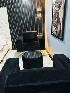 A modern living room with a black sofa, a round coffee table, and a wall-mounted speaker. - Montenegro Suit Hotel (Eyup)