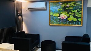 A modern hotel room with a bed, two black armchairs, a small table, an air conditioning unit, and a painting of water lilies on the wall. - Montenegro Suit Hotel (Eyup)