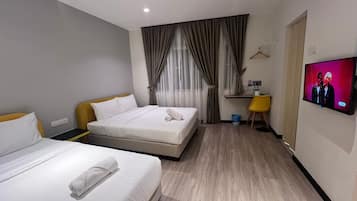 Habitación de hotel con dos camas, un escritorio, un televisor y una ventana con cortinas.