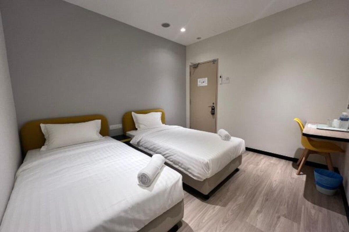 A hotel room with two beds, a desk, and a chair.