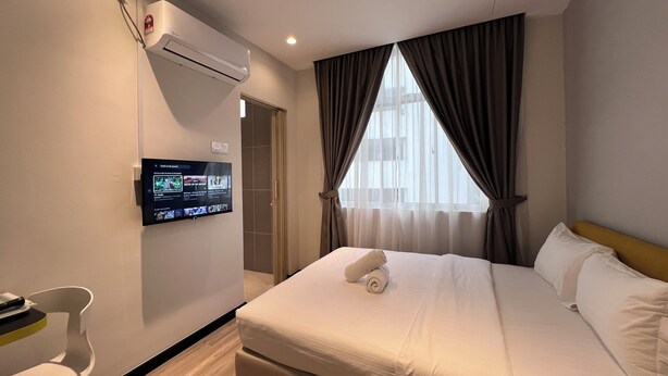 A hotel room with a bed, a TV mounted on the wall, a chair, and a window with curtains. - Havona Hotel @ CIQ Johor Bahru - Self Check-In (Johor Bahru)
