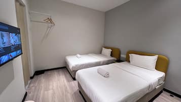 Una habitación de hotel con dos camas, un televisor montado en la pared y piso de madera.