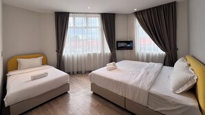 A hotel room with two beds, a flat-screen TV mounted on the wall, and a large window with curtains. - Havona Hotel @ CIQ Johor Bahru - Self Check-In (Johor Bahru)