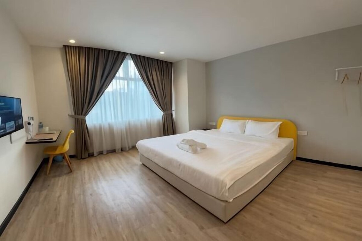 A hotel room with a bed, a desk, a chair, and a television.