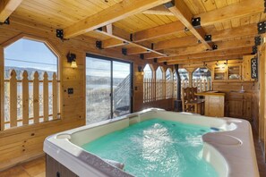 Une cabane en bois dotée d’un bain à remous, de murs en bois et de grandes fenêtres.