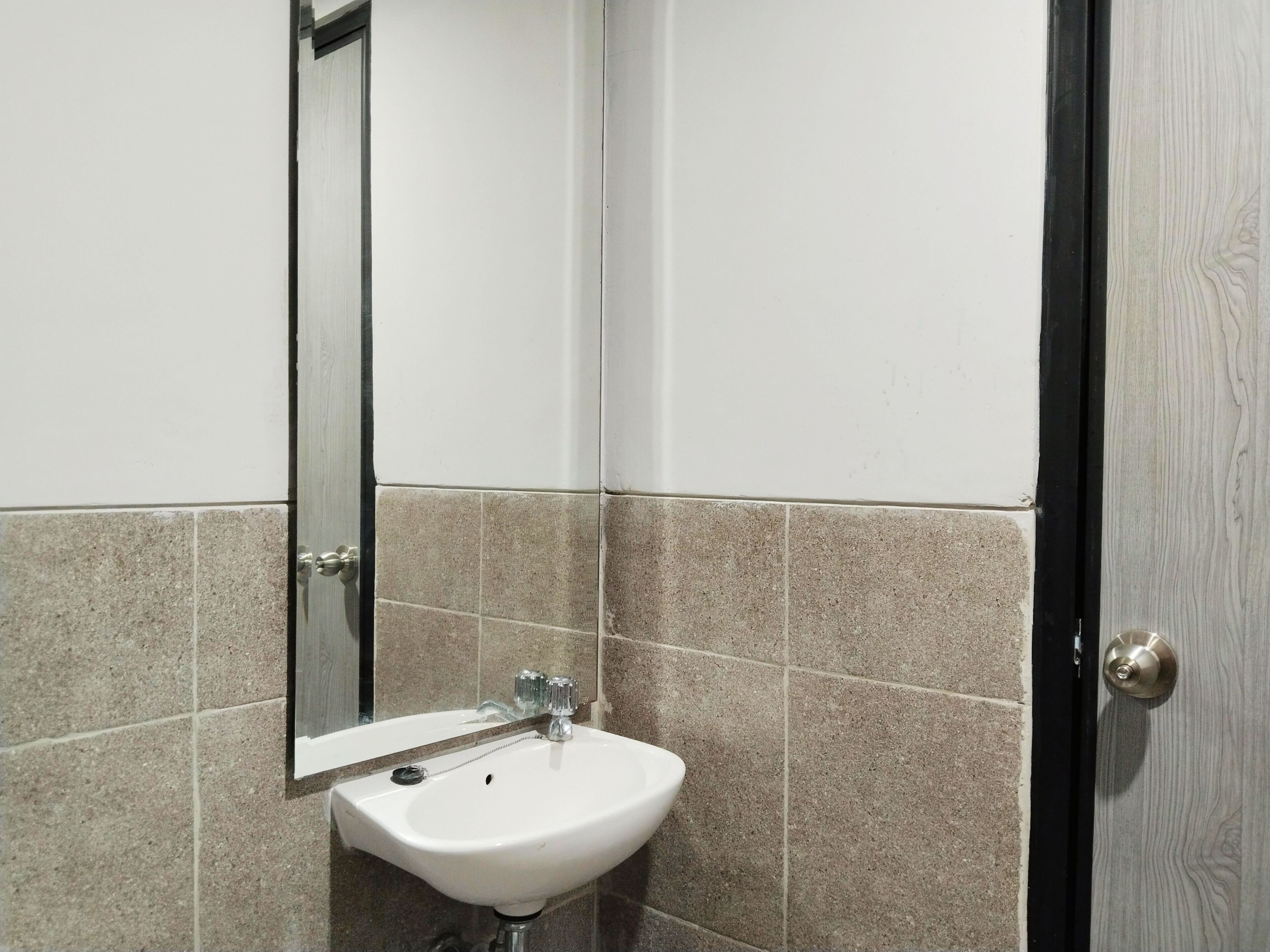 A bathroom with a white sink, a mirror, and beige tiles.