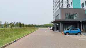 A modern building with a parking area and a blue car parked near the entrance.